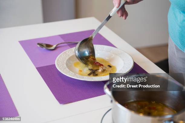 woman filling noodle soup in a soup plate on dining table - menschliches körperteil foto e immagini stock