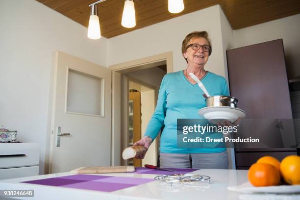 happy old woman with pot, bread and soup plates in her hands - altötting stock-fotos und bilder