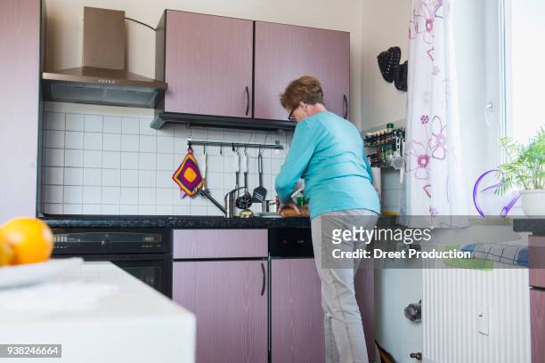 old woman working with bread in the kitchen - trinken flasche foto e immagini stock