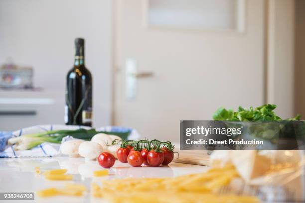 tomatoes, mushrooms, salad, spring onions and a bottle of red wine on kitchen table - tisch essen stockfoto's en -beelden