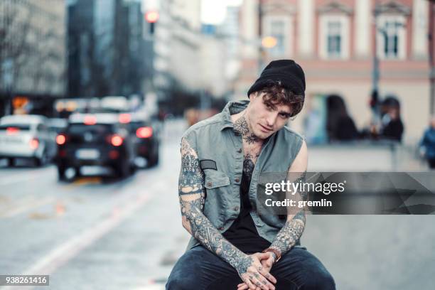 joven sentado en la calle - shy fotografías e imágenes de stock