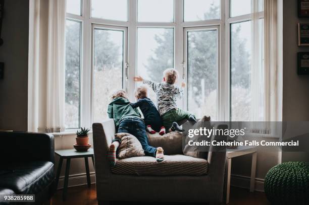 three kids looking out a large window - family with three children stock pictures, royalty-free photos & images