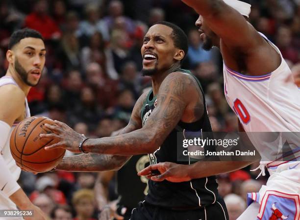 Brandon Jennings of the Milwaukee Bucks moves between Denzel Valentine and Noah Vonleh of the Chicago Bulls at the United Center on March 23, 2018 in...