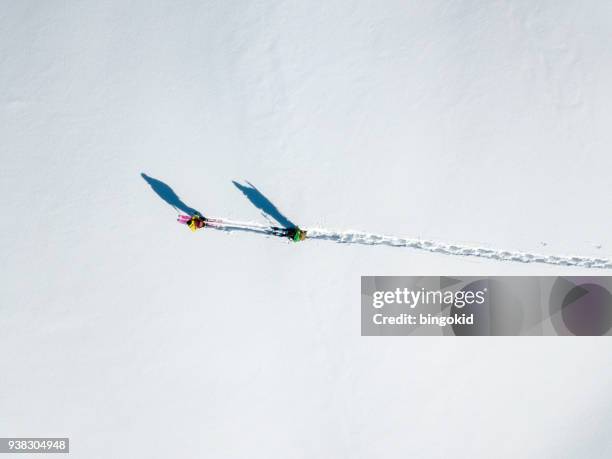 two hikers with long shadows walking over snow (aerial shot) - winter footpath stock pictures, royalty-free photos & images