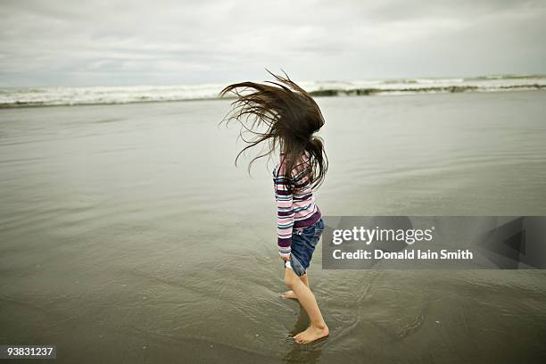 girl throws back her long hair at the beach - girl blowing sand stock-fotos und bilder