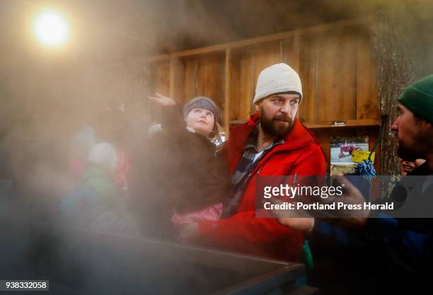Linnea Miller left, runs her hand through the steam from the evaporator as her father Brent, center, speaks with Adam Parsons, right, during a tour...