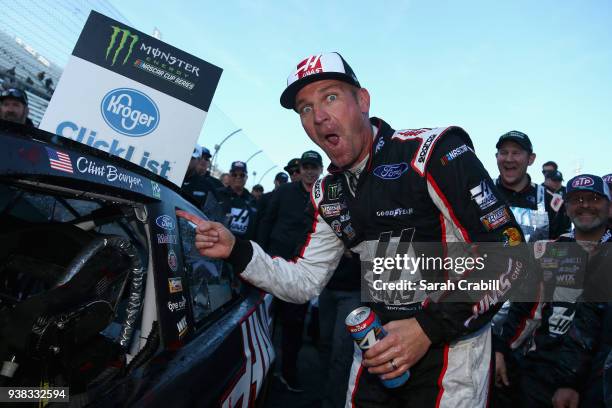 Clint Bowyer, driver of the Haas Automation Demo Day Ford, poses with the winner's decal on his car in Victory Lane after winning the weather delayed...