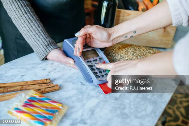 closeup of hand of person paying in store with credit card - spicy j fotografías e imágenes de stock