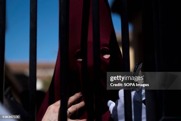 Penitent from the "Trabajo y Luz" brotherhood waits behind the gate to take part in the Holy Monday procession. Every year thousands of christians...