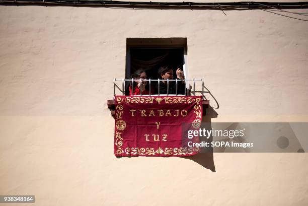 Two kids look out the "Cristo del Trabajo" during the procession of Holy Monday in Granada. Every year thousands of christians believers celebrates...