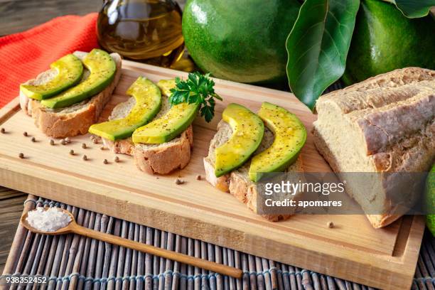 snack oder vorspeise avocadoscheiben bruschetta mit olivenöl, pfefferminze und salz - aguacates stock-fotos und bilder