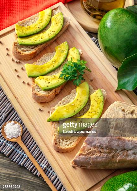 snack or appetizer of avocado slices bruschetta with olive oil, peppermint and salt - avocato oil stock pictures, royalty-free photos & images