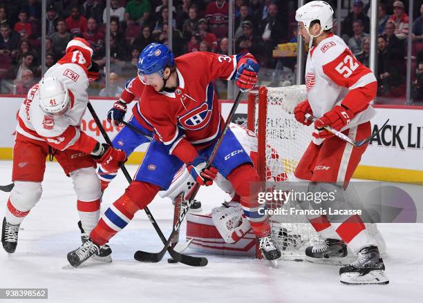 Jared Coreau and Luke Glendening of the Detroit Red Wings defend the net against Michael McCarron of the Montreal Canadiens in the NHL game at the...
