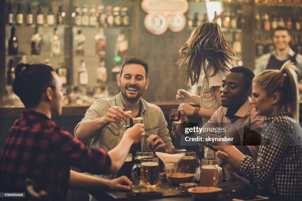 Grupo de amigos felices divertirse mientras tostado con shots de vodka en un bar.