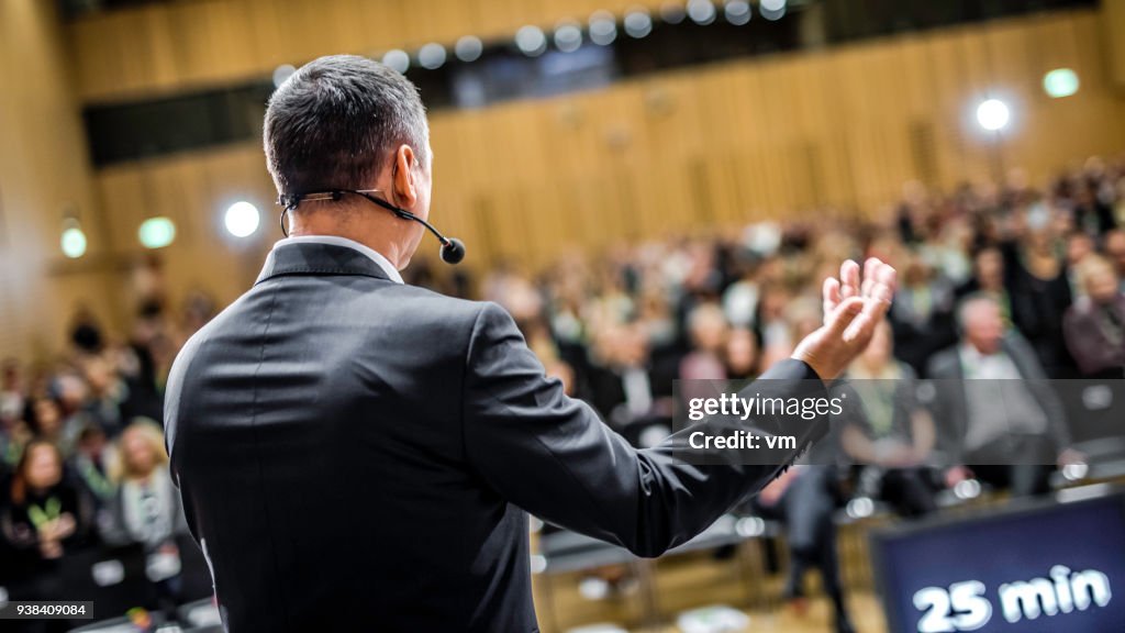 Businessman givng lecture at a full conference hall