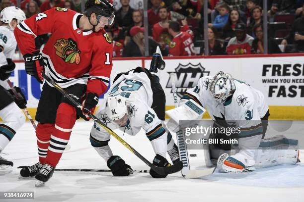 Justin Braun of the San Jose Sharks falls in between Victor Ejdsell of the Chicago Blackhawks and goalie Martin Jones in the first period at the...