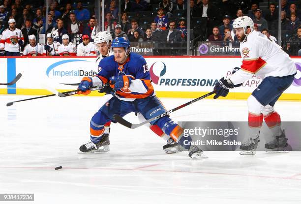 Mathew Barzal of the New York Islanders tries to create a shot amid pressure from Jonathan Huberdeau and Keith Yandle of the Florida Panthers during...