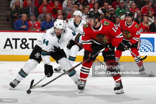 Marc-Edouard Vlasic of the San Jose Sharks and Alex DeBrincat of the Chicago Blackhawks chase the puck in the second period at the United Center on...