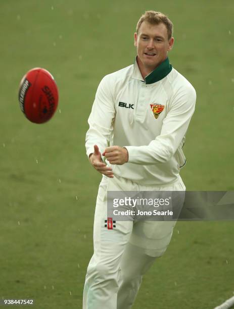 Tasmania player George Bailey plays with a football during a rain delay during day five of the Sheffield Shield final match between Queensland and...