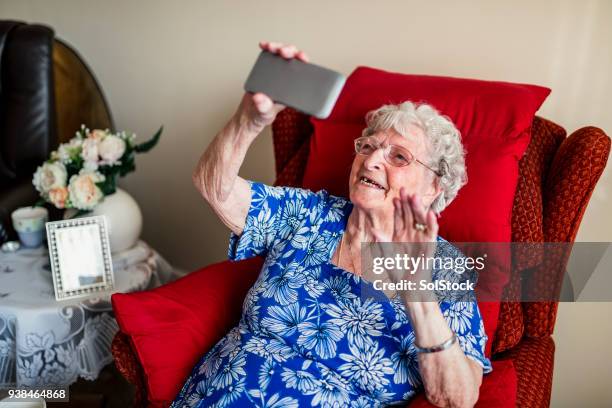 ältere frau mit einem mobiltelefon - international women day stock-fotos und bilder