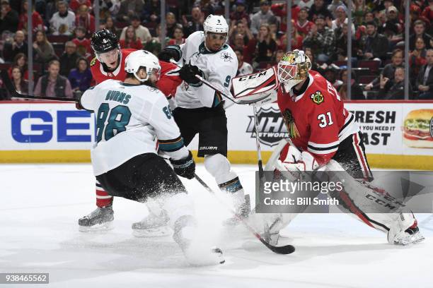 Connor Murphy of the Chicago Blackhawks works to get at the puck against Brent Burns and Evander Kane of the San Jose Sharks, in front of goalie...