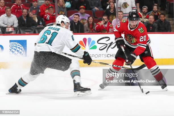Brandon Saad of the Chicago Blackhawks controls the puck against Justin Braun of the San Jose Sharks in overtime at the United Center on March 26,...