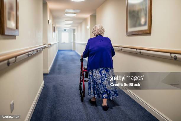 femme senior avec walker dans un foyer de soins - hospice photos et images de collection