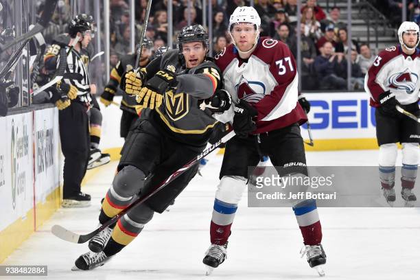 Jon Merrill of the Vegas Golden Knights and J.T. Compher of the Colorado Avalanche skate to the puck during the game at T-Mobile Arena on March 26,...
