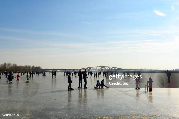 mensen schaatsen op een bevroren meer naast de rivier de ijssel in de buurt van zwolle - ijssel stockfoto's en -beelden