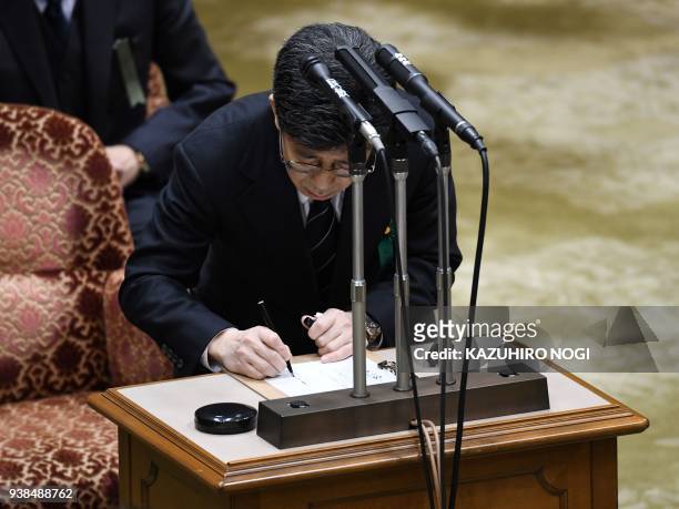 Nobuhisa Sagawa, former senior Finance Ministry official, signs a declaration as a witness as he attends an Upper House budget committee meeting to...