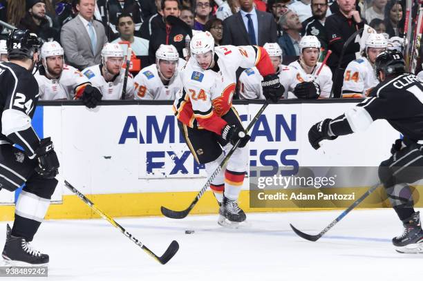 Travis Hamonic of the Calgary Flames handles the puck against Kyle Clifford and Derek Forbort of the Los Angeles Kings at STAPLES Center on March 26,...