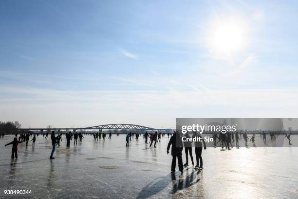 mensen schaatsen op een bevroren meer naast de rivier de ijssel in de buurt van zwolle - ijssel stockfoto's en -beelden