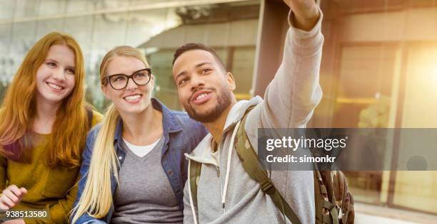 studenti che si fanno selfie con il telefono nel campus universitario - pulsante di apertura o di chiusura foto e immagini stock