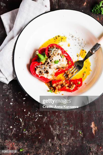 red bell pepper stuffed with pork and beef meat, carrot, onion with grated cheese sprinkled with spices and fresh parsley in a plate on a wooden table, top view - roasted red onion fotografías e imágenes de stock