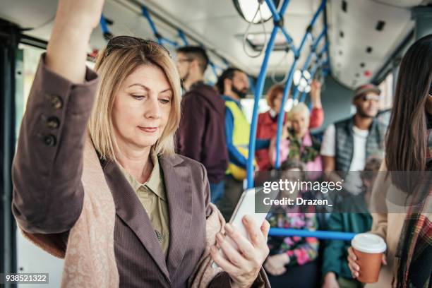 businesswoman reading news feed on smartphone while traveling - crowded bus stock pictures, royalty-free photos & images