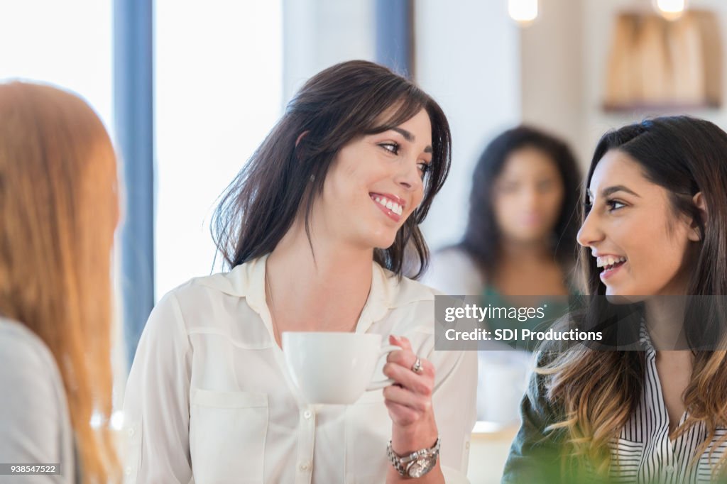 Three female friends enjoying coffee shop conversation
