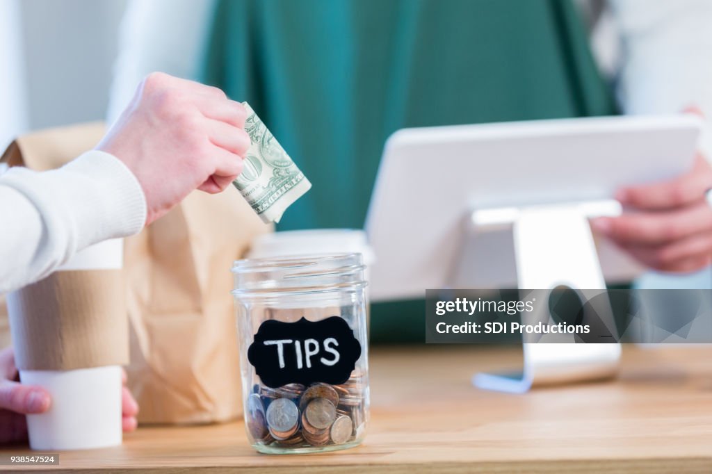 Unrecognizable coffee shop customer using tip jar