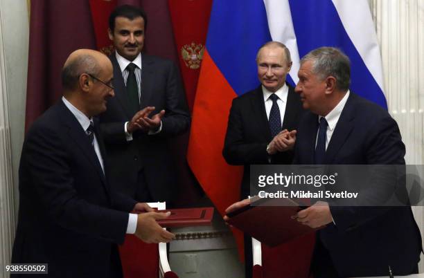 Russian President Vladimir Putin looks on as Rosneft's President Igor Sechin greets President of Research and Developmet at Qatar Foundation for...