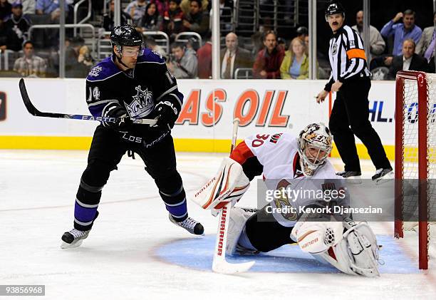 Brian Elliott goalkeeper of the Ottawa Senators makes a glove save on a shot on goal as Justin Williams of the Los Angeles Kings looks on during the...