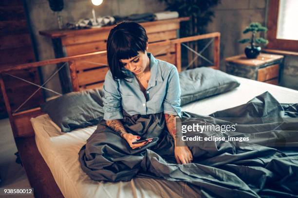 lonely lesbian girl in bed texting - sad gay person stock pictures, royalty-free photos & images