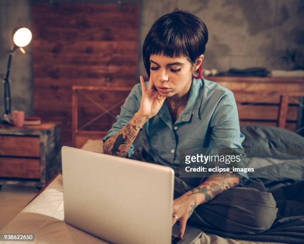 eenzame vrouw in bed met behulp van internet op zoek naar partner - lesbian dating stockfoto's en -beelden