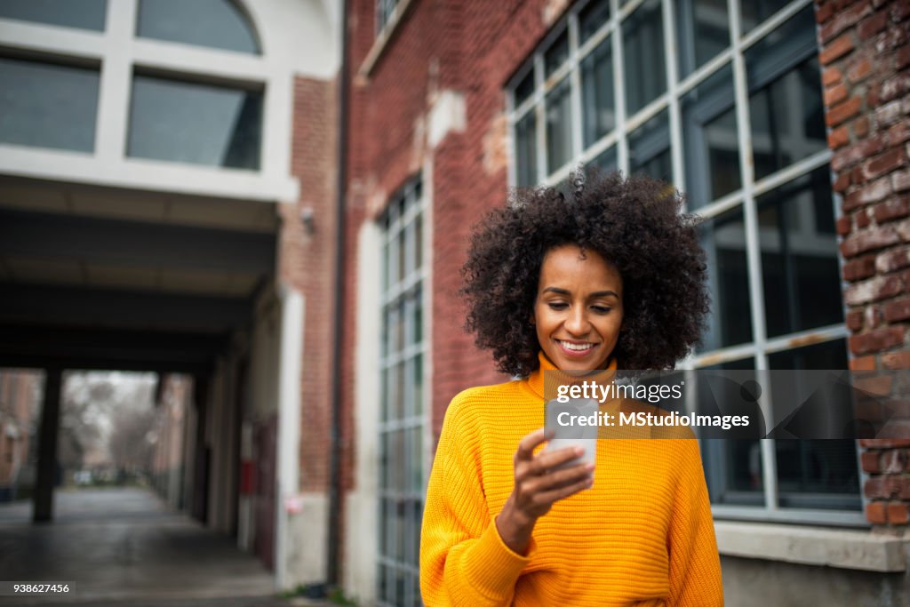 Smiling woman using mobile phone.