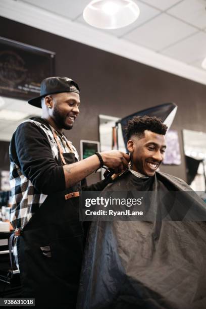 barber giving a haircut in his shop - barbers stock pictures, royalty-free photos & images
