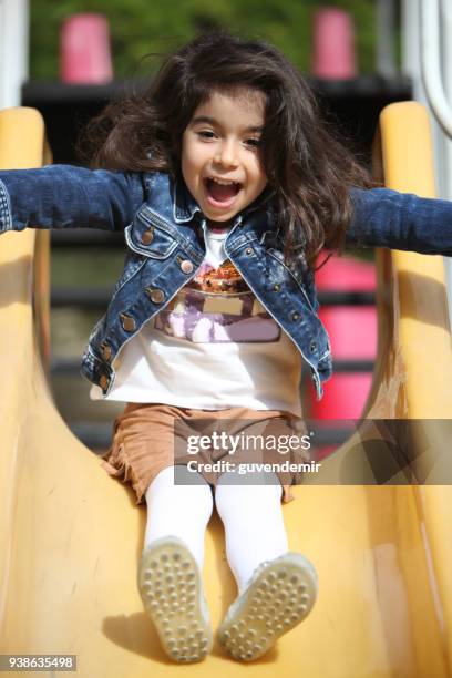 cheerful little girl having fun while sliding at park on playground - climbing frame stock pictures, royalty-free photos & images