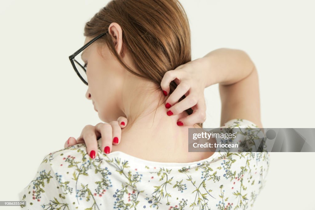 Close up view of woman scratching her neck.