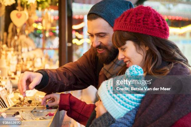 parents show child ornaments at christmas stall. - craft market stock pictures, royalty-free photos & images