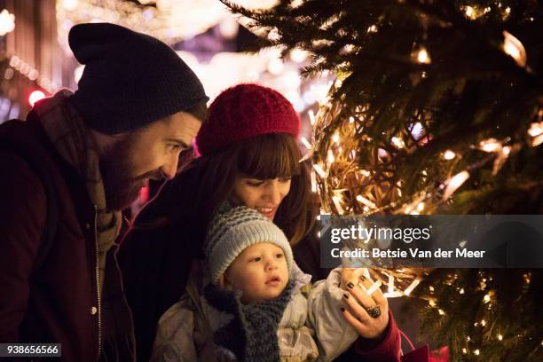 parents show their child the christmas lights on christmas tree in city centre. - london winter stockfoto's en -beelden