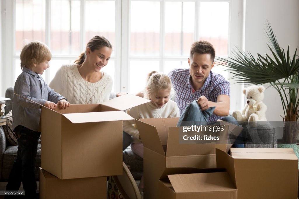 Young happy family with children packing boxes on moving day