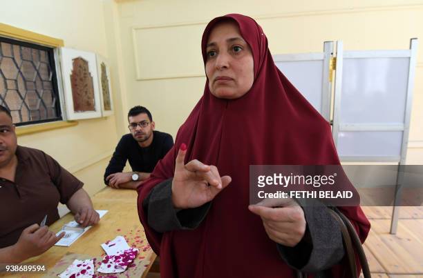 An Egyptian woman shows her ink-stained finger after casting her vote at a polling station in the Nile Delta City of Tanta, 120 kilometres north of...