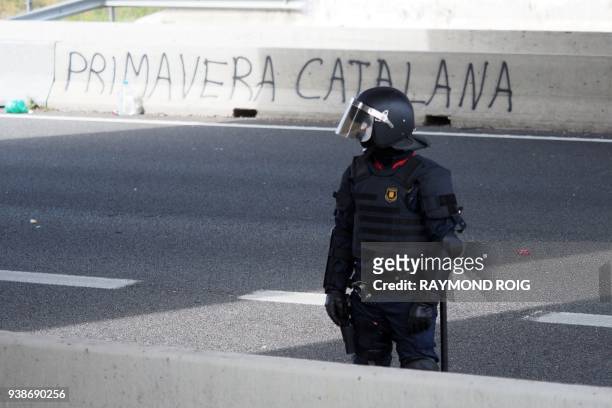 Spanish riot policeman stands in front of a sign reading 'Catalan Spring' after police broke up a road blockade set up by Catalan separatists on AP-7...